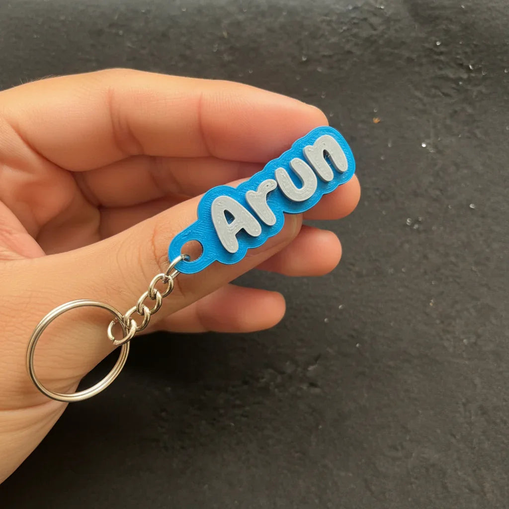 Personalized blue keychain with 'Arun' text, held by hand, The Sculpt Studio custom accessory